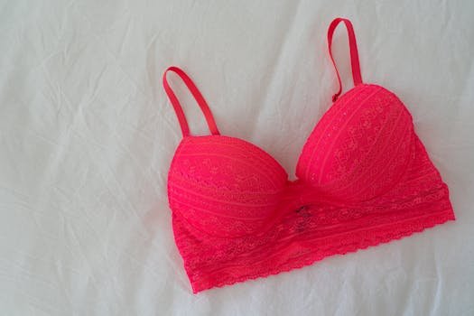 Top 10 Sfaturi pentru Alegerea Cea Mai Confortabilă Lenjerie Intimă 3 Bright lace pink bra laid flat on soft white sheet.