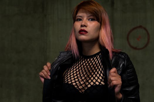 Striking portrait of a woman with pink hair and black leather jacket in a studio setting.