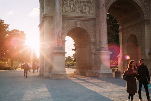 A romantic scene with sunrays shining through a Parisian archway, featuring people strolling.