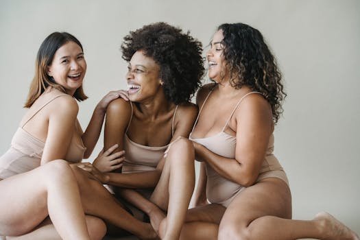 Three women enjoying a moment of laughter and body positivity in a studio setting.