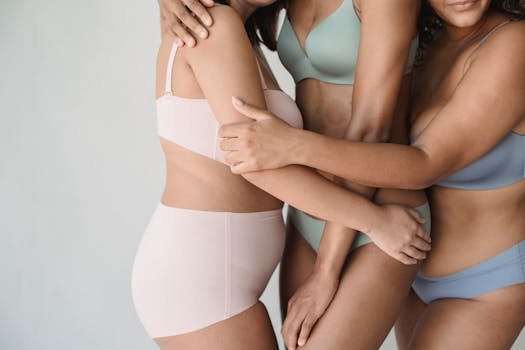 Întrebări Frecvente Despre Lenjeria Intimă Damă și Îmbrăcămintea Feminină: Ghidul Complet 3 Three women embracing, showcasing diverse beauty in minimalist lingerie against a white background.