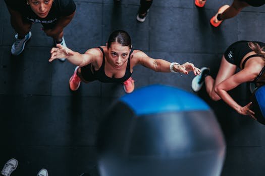 A dynamic overhead shot of women exercising with a medicine ball in a gym setting, demonstrating strength and focus.