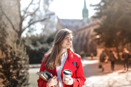 Rochii Elegante Nuntă 2026: Ghidul Complet pentru un Look Memorabil + Bonus: Pantofi Stiletto Dama Perfecți pentru Eveniment! 3 Smiling woman in red coat with coffee and books, enjoying leisure time outdoors on a university campus.