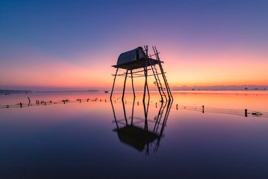 Rochii Elegante Nuntă 2026: Ghidul Complet pentru un Look Memorabil + Bonus: Pantofi Stiletto Dama Perfecți pentru Eveniment! 4 Stunning silhouette of a Vietnamese stilt hut reflecting in tranquil waters at sunset.