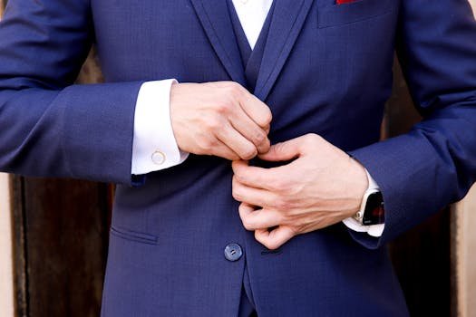 Close-up of a man's hands fastening a navy suit button, showcasing elegance and style.