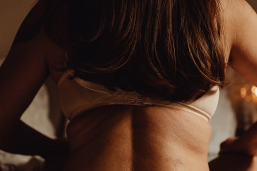 Top 5 Tendințe Incitante în Lenjeria Intimă și Îmbrăcămintea Feminină în 2024 2 Detailed close-up image of a woman's back wearing a bra in warm lighting.