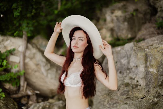 A young woman with red hair wearing a sun hat enjoys a summer day outdoors.