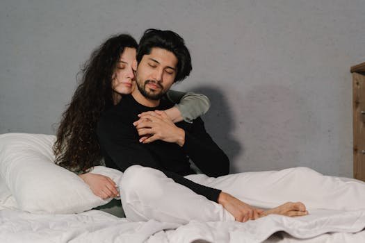A couple lovingly embracing in bed, capturing a moment of intimacy and relaxation indoors.