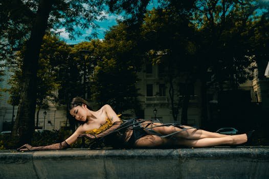 A woman in an artistic pose lying outdoors in a dramatic, moody setting.