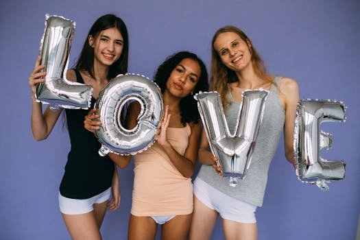 Three diverse women holding silver love balloons against a purple backdrop. Friendship and celebration theme.