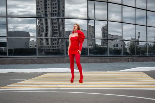 Cum să Alegi Corsetul Modelator pentru Ocazii Speciale Potrivit Siluetei Tale 3 Stylish woman in bold red dress stands confidently in modern urban environment with glass reflections.